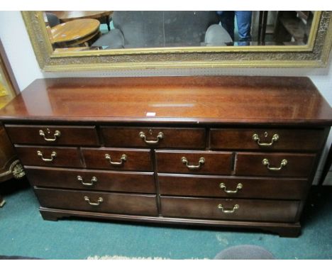 A MAHOGANY LOWBOY the rectangular top above an arrangement of seven drawers with brass drop handles on bracket feet
