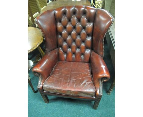 A HIDE UPHOLSTERED WING BACK LIBRARY CHAIR with deep button upholstered back and seat with scroll arms on moulded legs