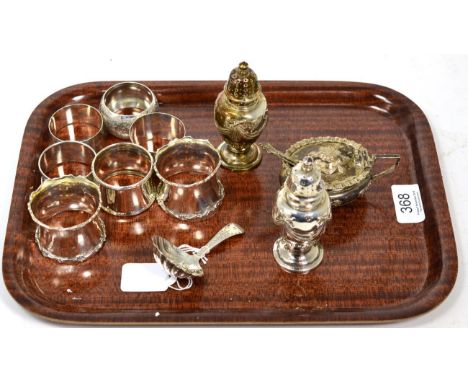 A silver caddy spoon; seven silver napkin rings; and a three piece condiment set