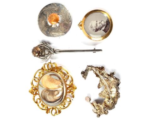 A mid nineteenth century hairwork brooch, of aranged hair on a mother-of-pearl ground, under glass, to a vine scroll frame, m