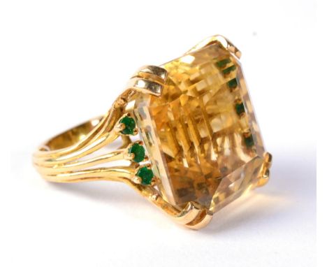 A citrine and emerald dress ring, an octagonal cut citrine in a double claw setting, to shoulders each set with three round c