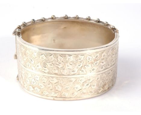 A Victorian silver cuff bangle, with chased leaf detail and a beaded edge, measures 5cm by 6cm inner diameter, 3.5cm wide, 40