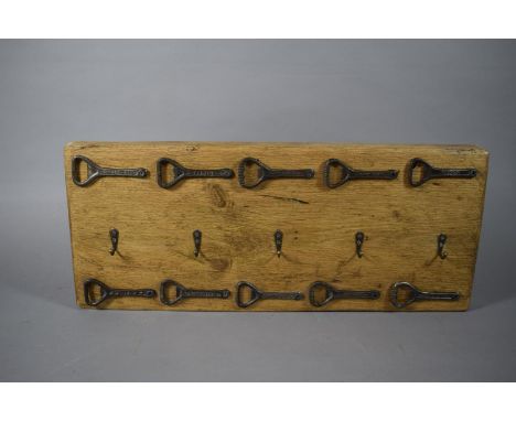A Wall Hanging Five Cup or Coat Rack Mounted with Ten Vintage Bottle Openers, 52cms Wide 