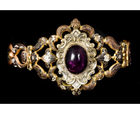 A Victorian enamel decorated mourning bangleOf pierced scrolling form, set with an amethyst coloured cabochon.  6 cm high.   