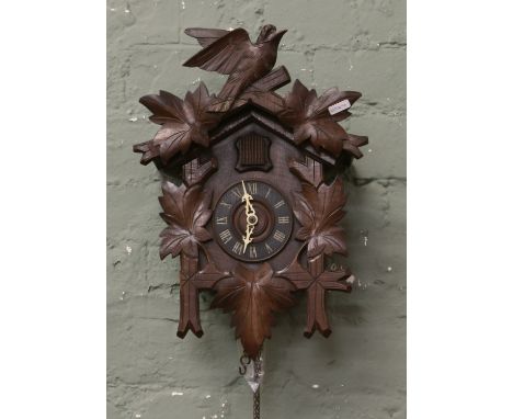 A Black Forest style cuckoo clock with pendulum and weights.