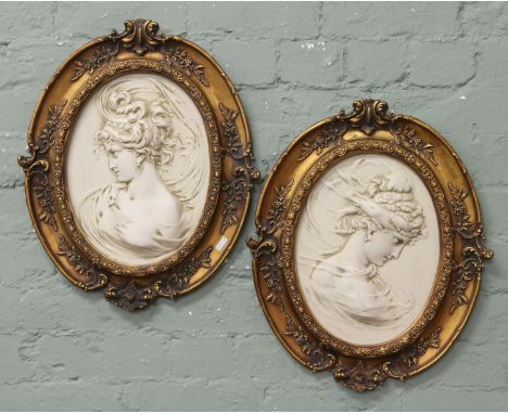 A pair of gilt framed portrait plaques of young maidens formed from reconstituted marble.