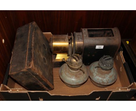 A VINTAGE MAGIC LANTERN, TWO OIL BURNING LAMPS AND A LIDDED TIN BOX (4)