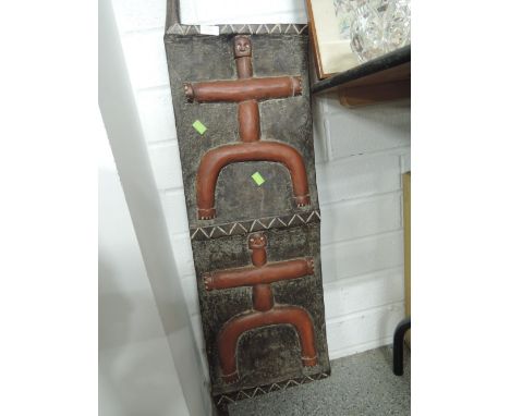 An ethnic tribal style wall plaque or shield hand carved with Aboriginal style figures