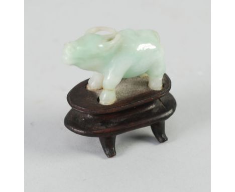 ORIENTAL CARVED GREEN JADE SMALL MODEL OF A BUFFALO, on wooden stand, 2" (5.1cm) high overall 