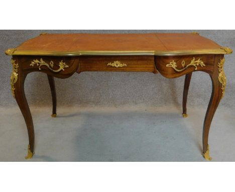 A walnut Louis XV style bureau plat of compact size with shaped tooled leather inset top with ormolu moulding above three fri