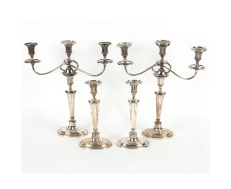Four Sheffield plate candlesticks of Adam style, two with three-light, two-branch attachments, 30.5cm and 47cm high