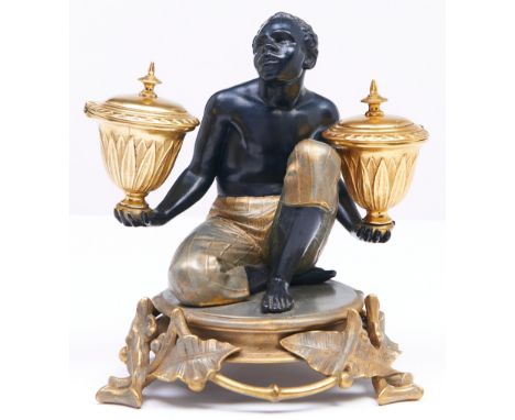 A French gilt, silvered and bronze patinated spelter slave figural encrier, late 19th c, in the form of a seated black man su