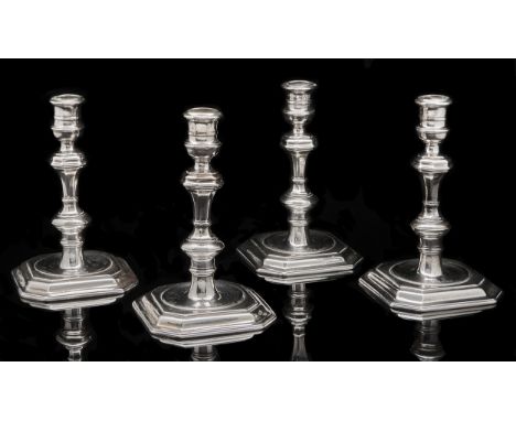 A set of four George I silver candlesticks, with banded sconce, the inverted baluster stem with compressed knop, on slightly 