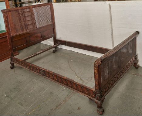 A carved walnut bedstead, early 20th c, in the form of a Louis XVI lit bateau, the gadrooned side rails carved with vitruvian