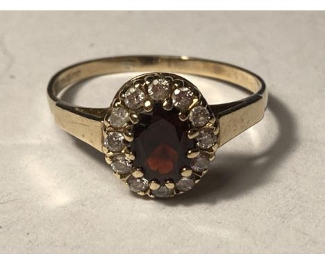 A 9 CARAT GOLD RING WITH CENTRE GARNET SURROUNDED BY CUBIC ZIRCONIAS SIZE R 