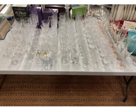 A VERY LARGE QUANTITY OF GLASSES, SOME CUT GLASS, TO INCLUDE CHAMPAGNE FLUTES, WINE, SHERRY, PORT, BRANDY, A DECANTER, ETC 