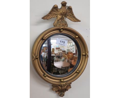 A small gilt convex wall mirror with eagle finial, 31cm high x 19cm wide Condition Report: Available upon request