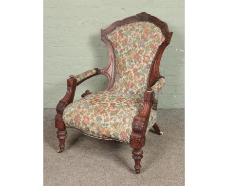 A Victorian carved mahogany armchair with tapestry upholstery.  Signs of damage/repair to frame, missing castor off back leg