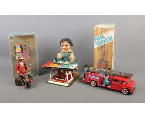 Three vintage tinplate toys to include Xylophone player, boxed Friction Fire Truck and boxed Duck riding a bicycle.  