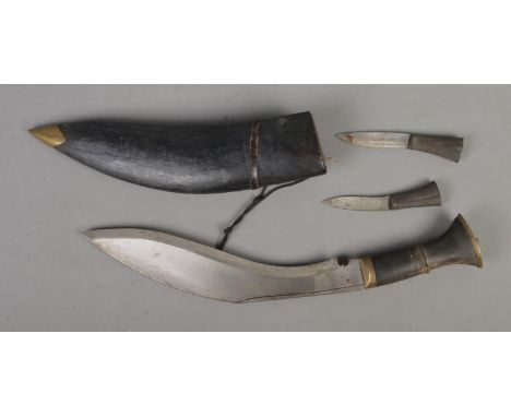 An Indian Kukri knife in scabbard with two smaller accompanying knives. Length of blade approximately 28cm. CANNOT POST OVERS