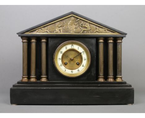 A black slate mantle clock, with Corinthian pillars and battle scene detailing. Features Arabic numeral dial and Junghans mov
