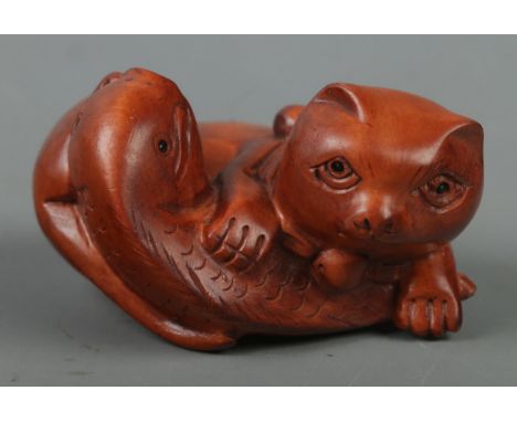 A hand carved hardwood netsuke of a cat with fish, signed to base.  