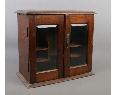 A vintage oak table top smokers cabinet with bevel edge glass doors.  