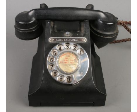 A vintage black bakelite rotary telephone.  