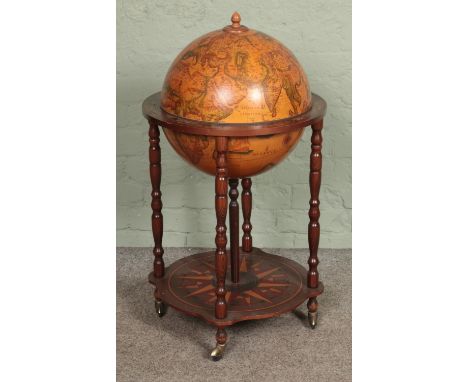 A Globe drinks cabinet, with turned oak supports, hinged top, horoscopic border and rotating base. Raised on casters. Height: