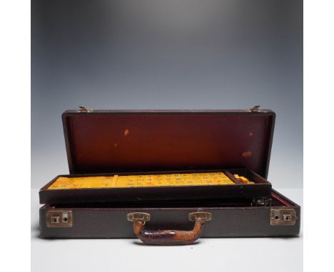 This vintage Mahjong set is presented in a charming brown faux reptile-skin case with a worn leather-wrapped handle and metal