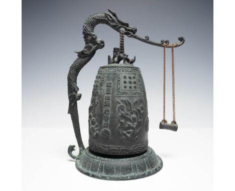 A Chinese bronze tabletop dragon bell, richly detailed and suspended beneath an arched dragon-form support. The bell body is 