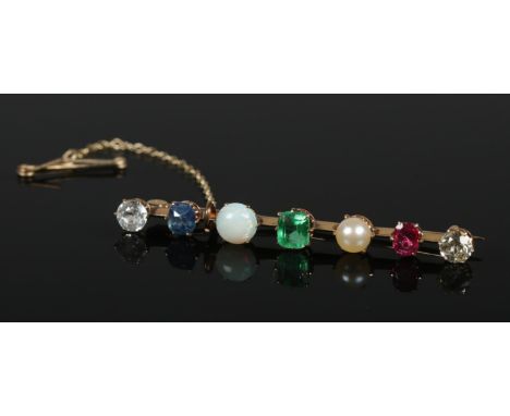 A yellow metal multi stone bar brooch set with two diamonds, a sapphire, an opal, an emerald and a ruby. 4.65g.  