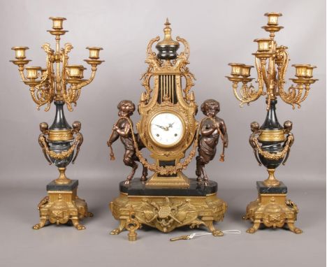 An Italian Imperial gilt metal and marble clock garniture. The clock of lyre form flanked by two cherubs. Candelabra 61cm.  