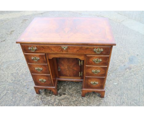 A figured walnut and banded kneehole desk of George I design, fitted one long drawer over six small drawers and central cupbo