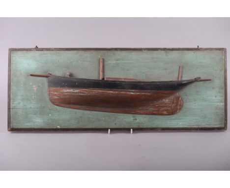 A carved and painted softwood scale model half hull of a yacht, on green painted backboard, 26" wideCondition:Slight paint lo