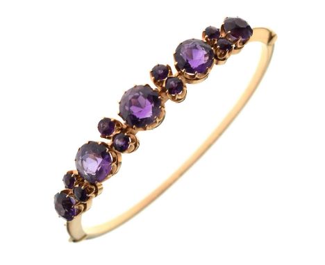 Amethyst set yellow metal snap bangle, claw-set with five larger amethysts (7.5mm diameter and smaller) flanking four pairs o