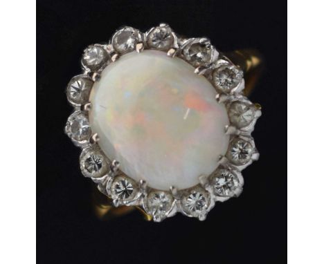 Opal and diamond cluster ring, the oval opal 11mm x 13mm approx, within a border of fourteen diamonds, the yellow metal mount