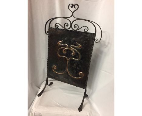 AN ARTS AND CRAFTS FIRE SCREEN WITH A DECORATIVE COPPER PANEL ON A WROUGHT IRON FRAME 