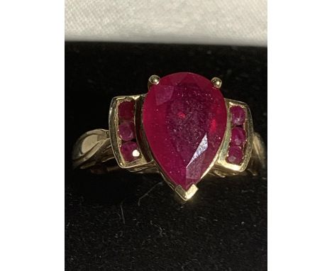 A 9 CARAT GOLD RING WITH A LARGE RED STONE AND THREE SMALL STONES EACH SIDE SIZE R GROSS WEIGHT 4.9 GRAMS 