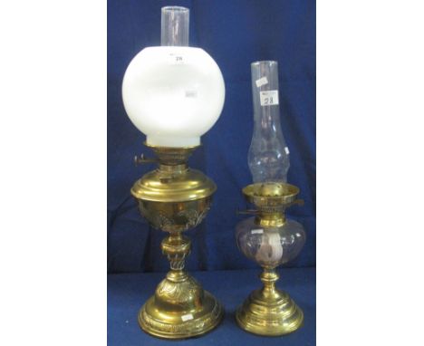 Brass double burner oil lamp with repousse decorated reservoir and domed pedestal base, together with another brass double bu