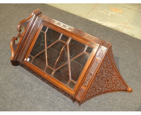 An Edwardian Chippendale style mahogany hanging corner cabinet,  the shaped shelf interior enclosed by an astragal glazed doo