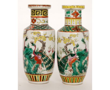 A pair of late 19th to early 20th Century Chinese rouleau vases each decorated with enamel peacocks amidst yellow blossom and
