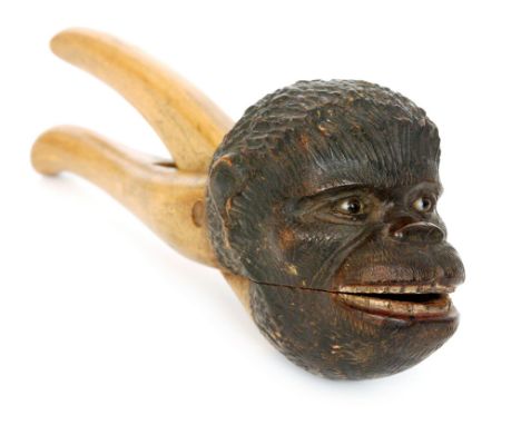 A late 19th Century beech nut cracker the head modelled as a monkey with glass set eyes and painted detail to teeth, length 2
