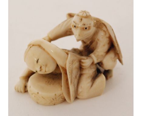 A small late 19th Century Japanese carved ivory netsuke modelled as an eagle crouching behind a male figure, width 3.5cm 