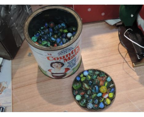 A vintage Ovaltine Country Maid tin containing a selection of marbles