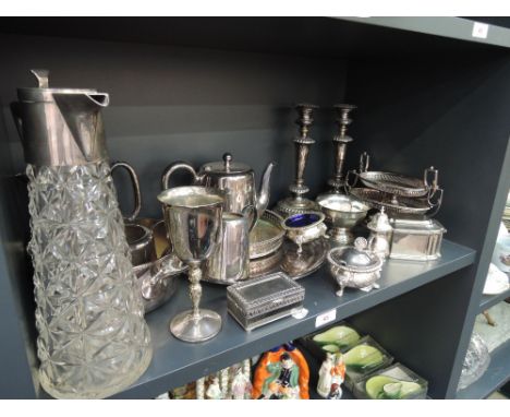 A shelf of platedware including candlesticks, claret jug, teaware etc