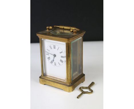An early 20th century brass cased carriage clock with beveled glass panels, white enamel face, complete with key.