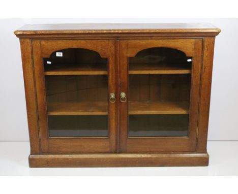 Early 20th century oak double door, glazed front bookcase with lions head handles, H 95cm, W 125cm, D 29cm,