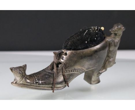 Early 20th century white metal pin cushion in the form of a shoe with ribbon laces and cat and dog detail, W 14cm