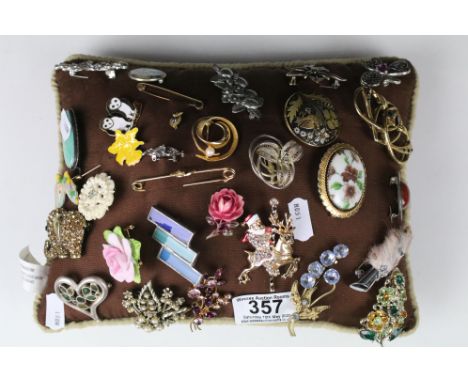 A collection of vintage and contemporary brooches mounted on a cushion 